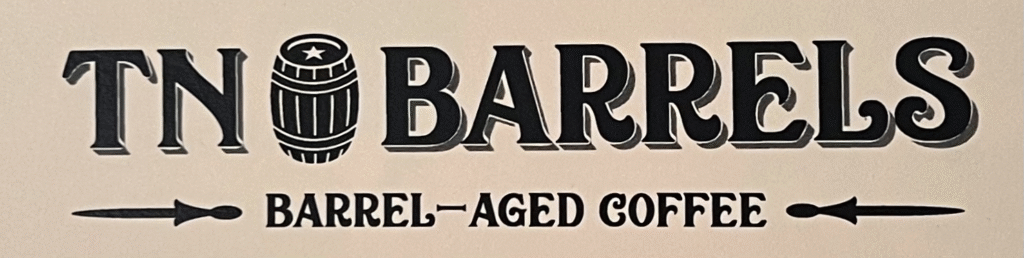 Vintage-style TN Barrels logo with a barrel icon between &ldquo;TN&rdquo; and &ldquo;Barrels,&rdquo; and the tagline &ldquo;Barrel-Aged Coffee&rdquo; centered below on a light background.